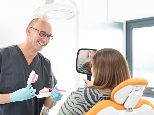 Dentist Showing Patient how To Brush Teeth